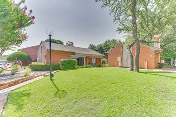 A house with a green lawn and a tree in front.